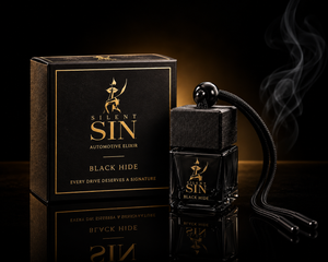 Silent Sin Automotive Elixir 'Black Hide' car fragrance bottle and packaging box on a dark reflective surface with a black cord, set against a black background with smoke. Ombre Leather Car Fragrance. Silent Sin Automotive Elixir Car Fragrance