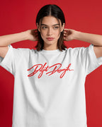 A woman wearing a white short-sleeve T-shirt with a red cursive script graphic across the chest, posed against a solid red background. Diljit Dosanjh Aura Tour India Tshirt.