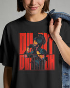 A woman wearing a black graphic t-shirt with a bold red and black print of Nitorious Atelier Diljit Dosanjh Aura Tour Collection., holding a denim jacket over her shoulder against a neutral gray background.