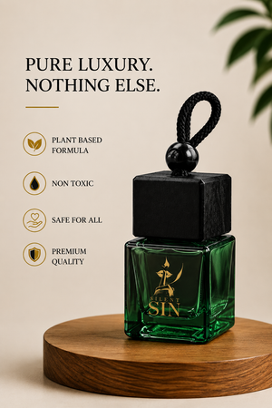 A green glass car air freshener bottle with a black cap and black hanging loop Forbidden Oud by SIlent Sin, displayed on a round wooden pedestal against a beige background. Text on the left highlights product benefits: plant based formula, non toxic, safe for all, and premium quality.