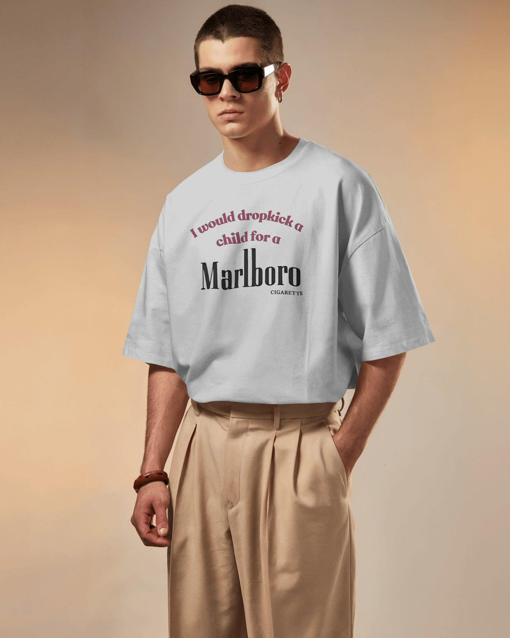 White oversized t-shirt featuring a bold, edgy text design. The statement 'I would dropkick a child for a Marlboro cigarette' is printed in a mix of red and black fonts, adding a rebellious streetwear vibe. Made from premium cotton, this t-shirt blends comfort with a striking, ironic aesthetic