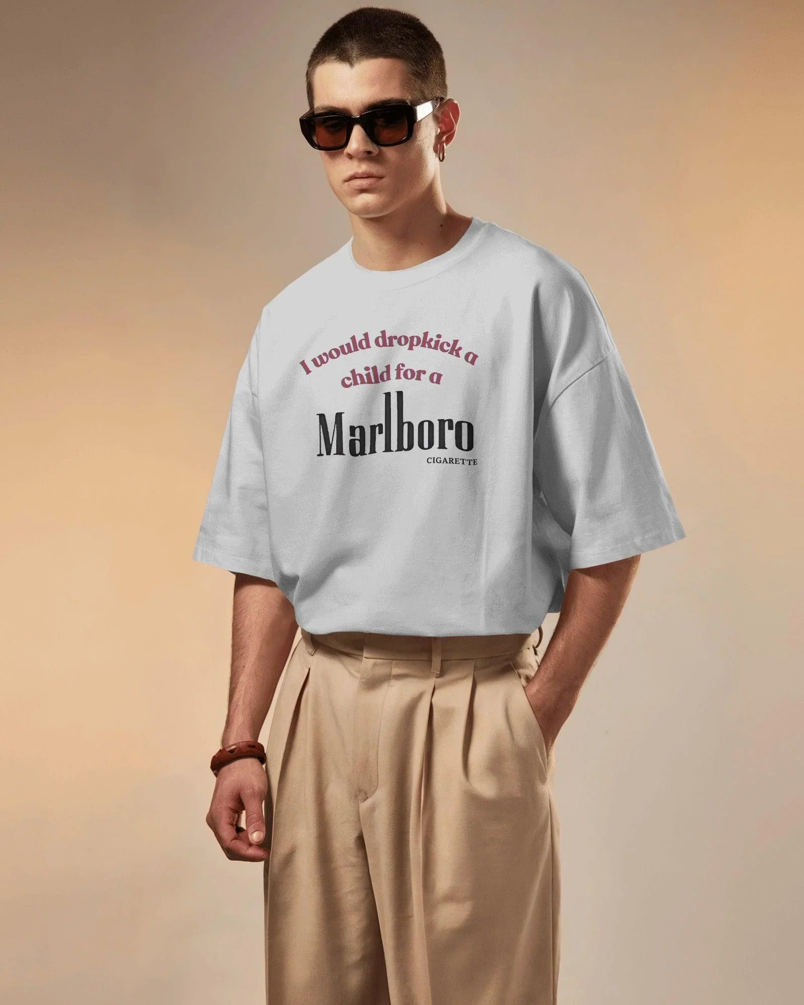 White oversized t-shirt featuring a bold, edgy text design. The statement 'I would dropkick a child for a Marlboro cigarette' is printed in a mix of red and black fonts, adding a rebellious streetwear vibe. Made from premium cotton, this t-shirt blends comfort with a striking, ironic aesthetic