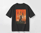 A black short-sleeve crewneck t-shirt featuring a large graphic print on the front with the text 'FRED AGAIN' in orange and yellow over a photo of a man playing a guitar. Fred Again India Concert collection