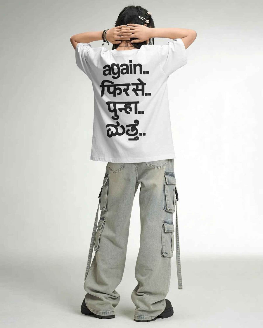 A model shown from behind wearing a white oversized t-shirt with black Hindi text, paired with light gray cargo pants, against a plain light gray background. Fred Again India Concert collection