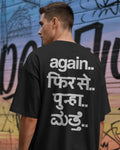 A man viewed from behind wearing a black t-shirt with white Hindi text printed on the back, set against a colorful graffiti wall. Fred Again India concert collection Tshirt 
