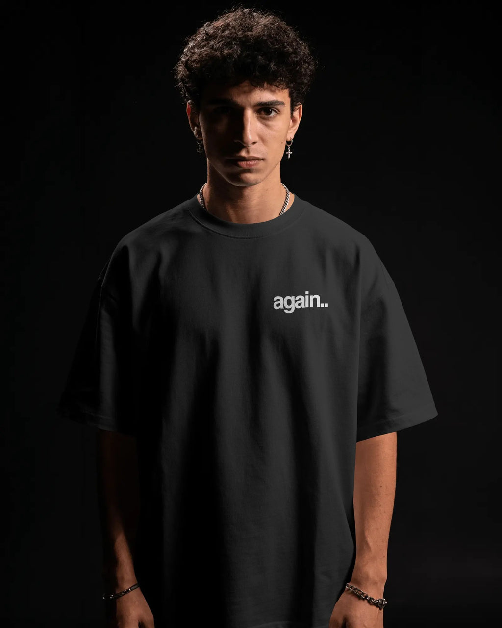A man wearing a black oversized t-shirt with the word 'again. Fred Again.. Tshirt India