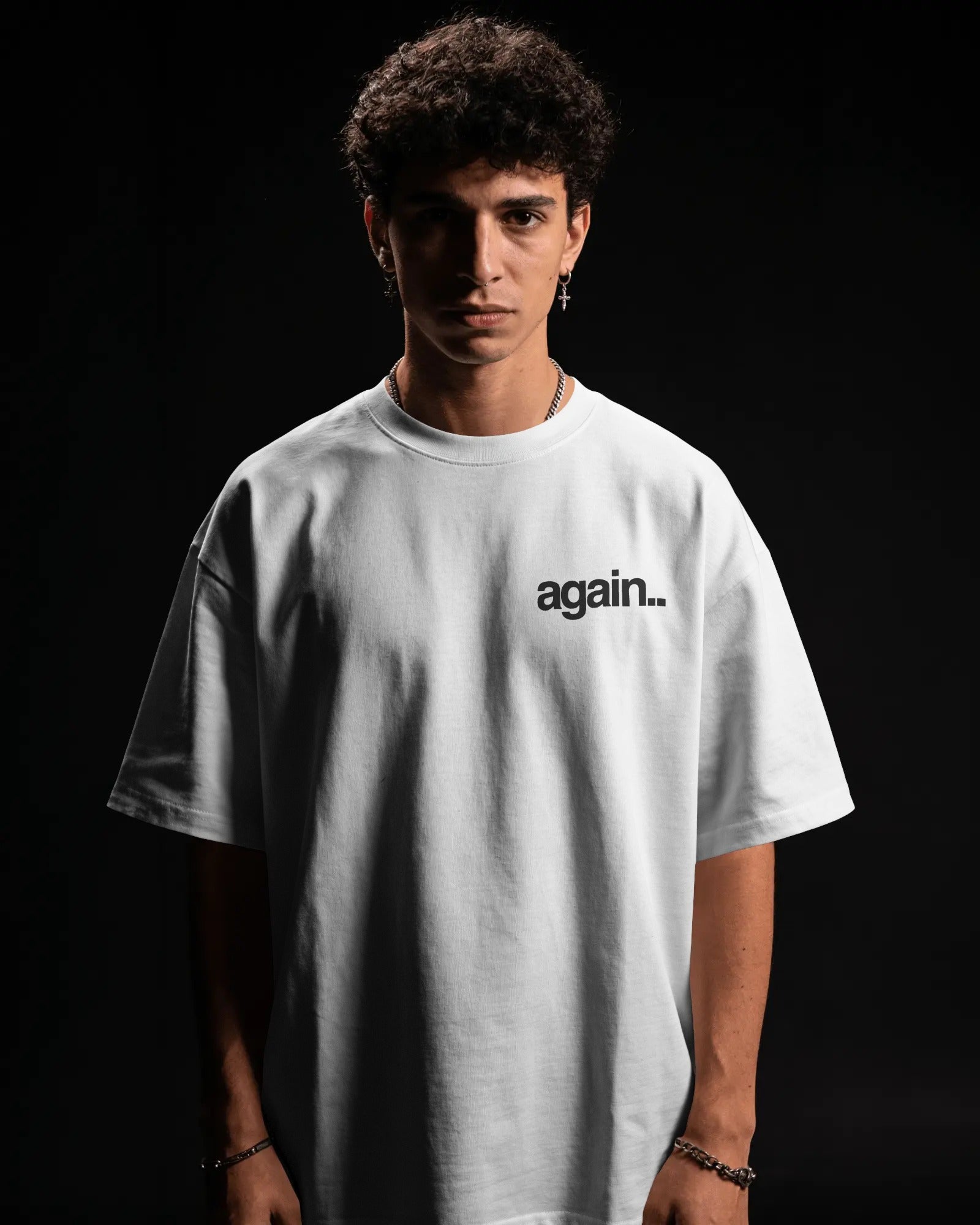 A man wearing an oversized white t-shirt with the word 'again. Fred Again.. Tshirt India