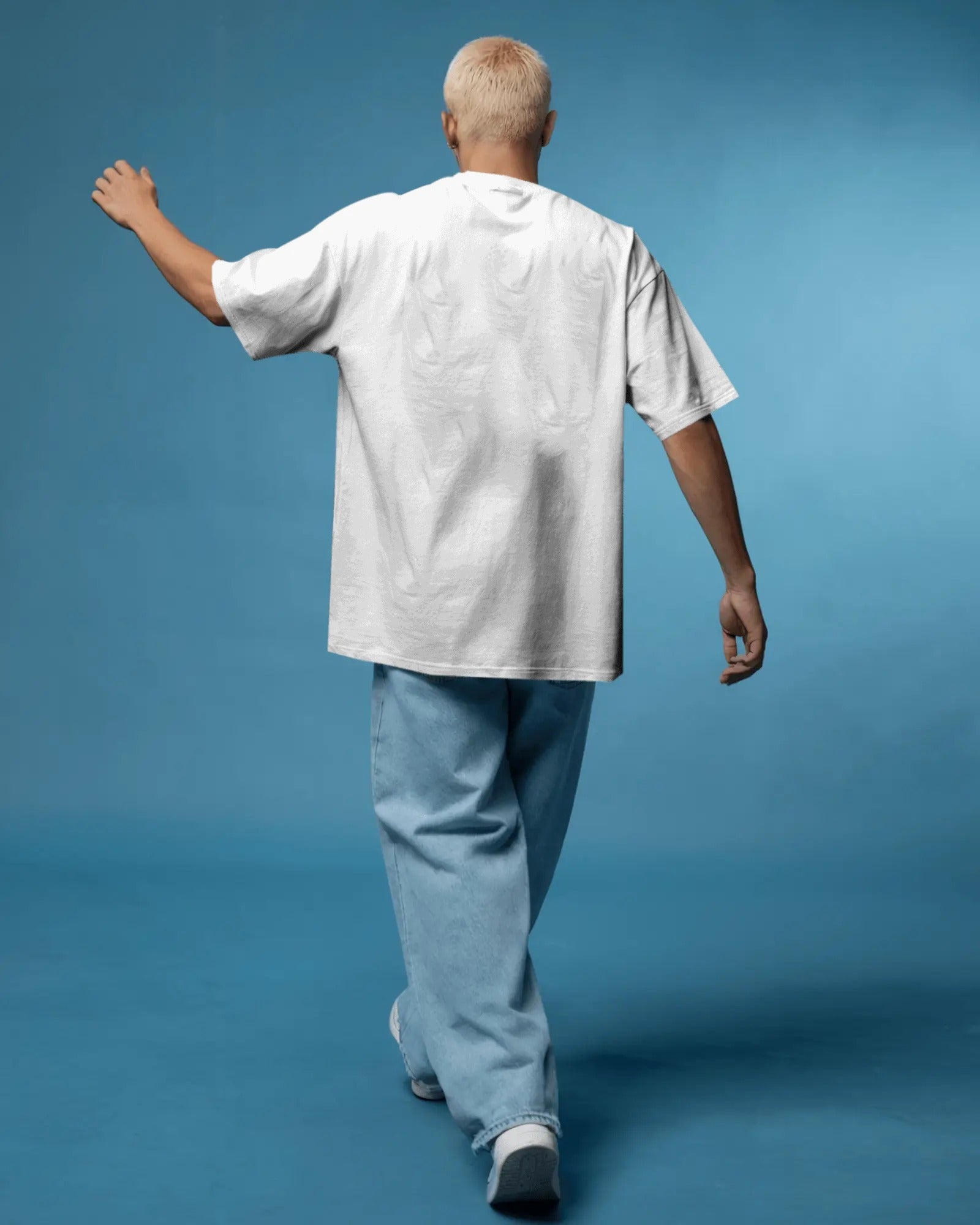 Person wearing a white shirt and light blue pants against a solid blue background