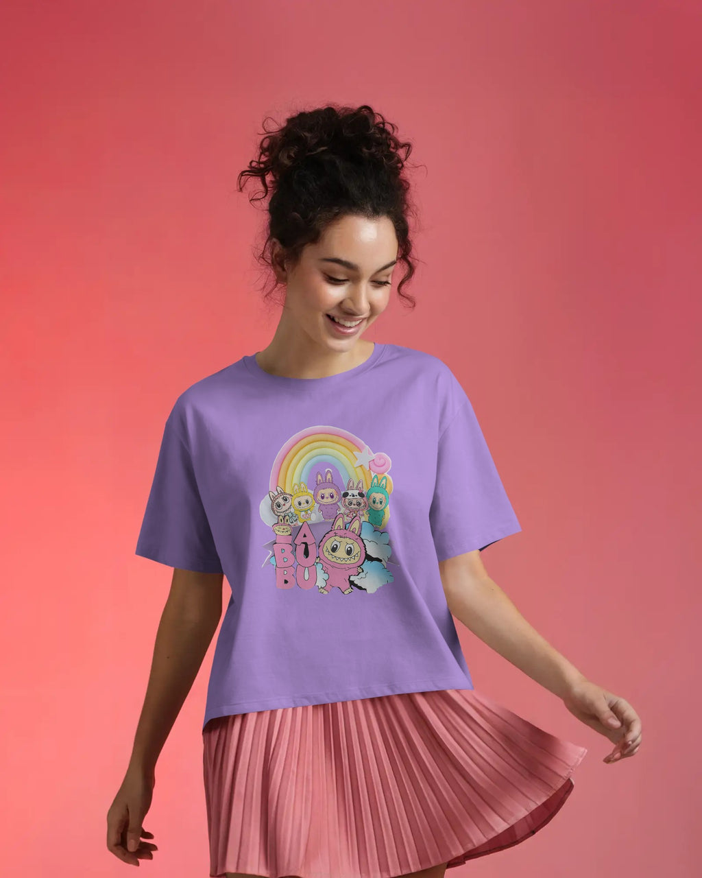 Woman wearing a Lavender Labubu t-shirt with cartoon characters and a rainbow on a pink background