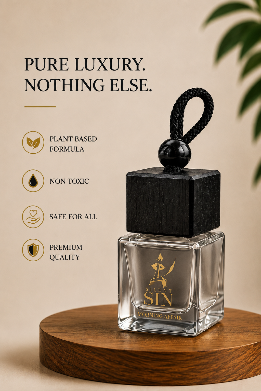 A clear glass perfume bottle with a black square cap and black hanging loop, placed on a round wooden pedestal against a warm beige background. The bottle has gold lettering that reads 'SILENT SIN' and 'Morning Affair.