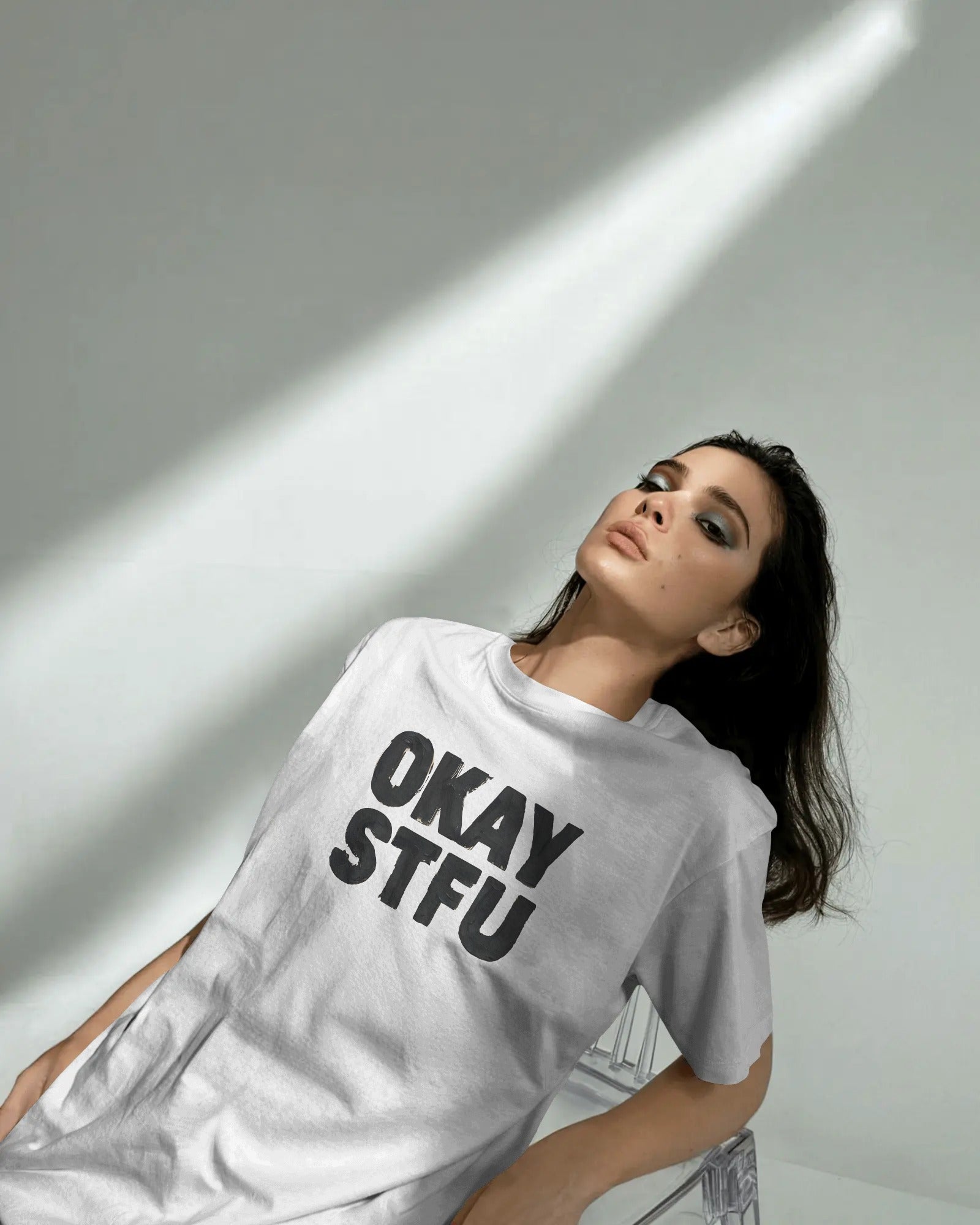Person wearing a white Nitorious Atelier AP Dhillon concert t-shirt with 'OKAY STFU' text against a light background
