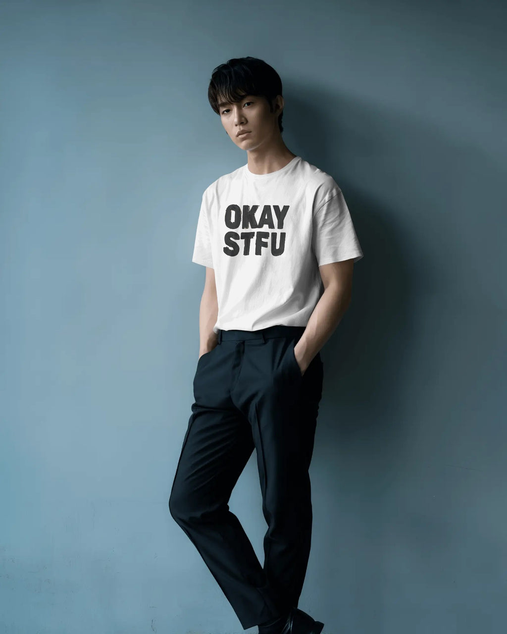 Person wearing a white Nitorious Atelier AP Dhillon concert t-shirt with 'OKAY STFU' text against a light background