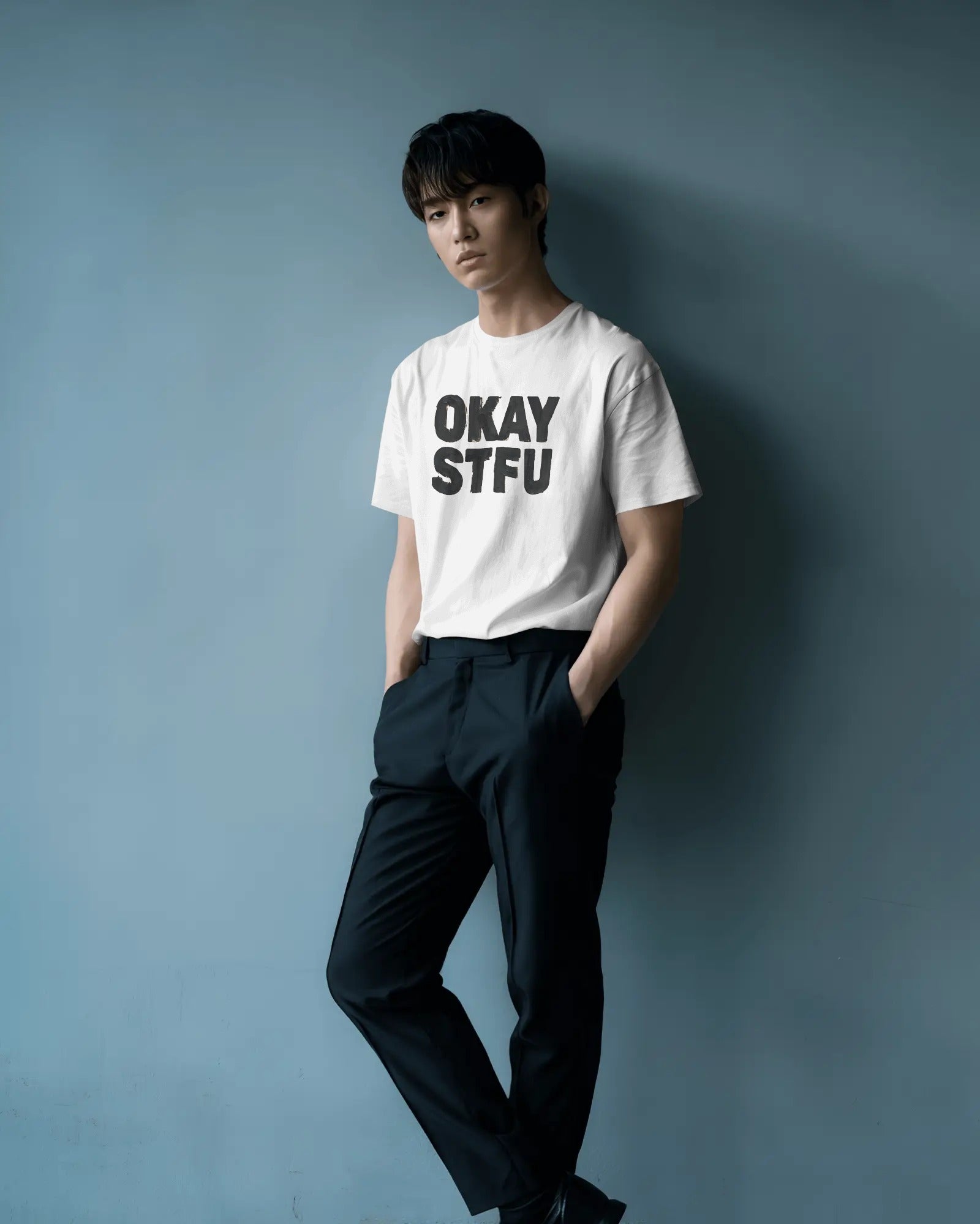 Person wearing a white Nitorious Atelier AP Dhillon concert t-shirt with 'OKAY STFU' text against a light background