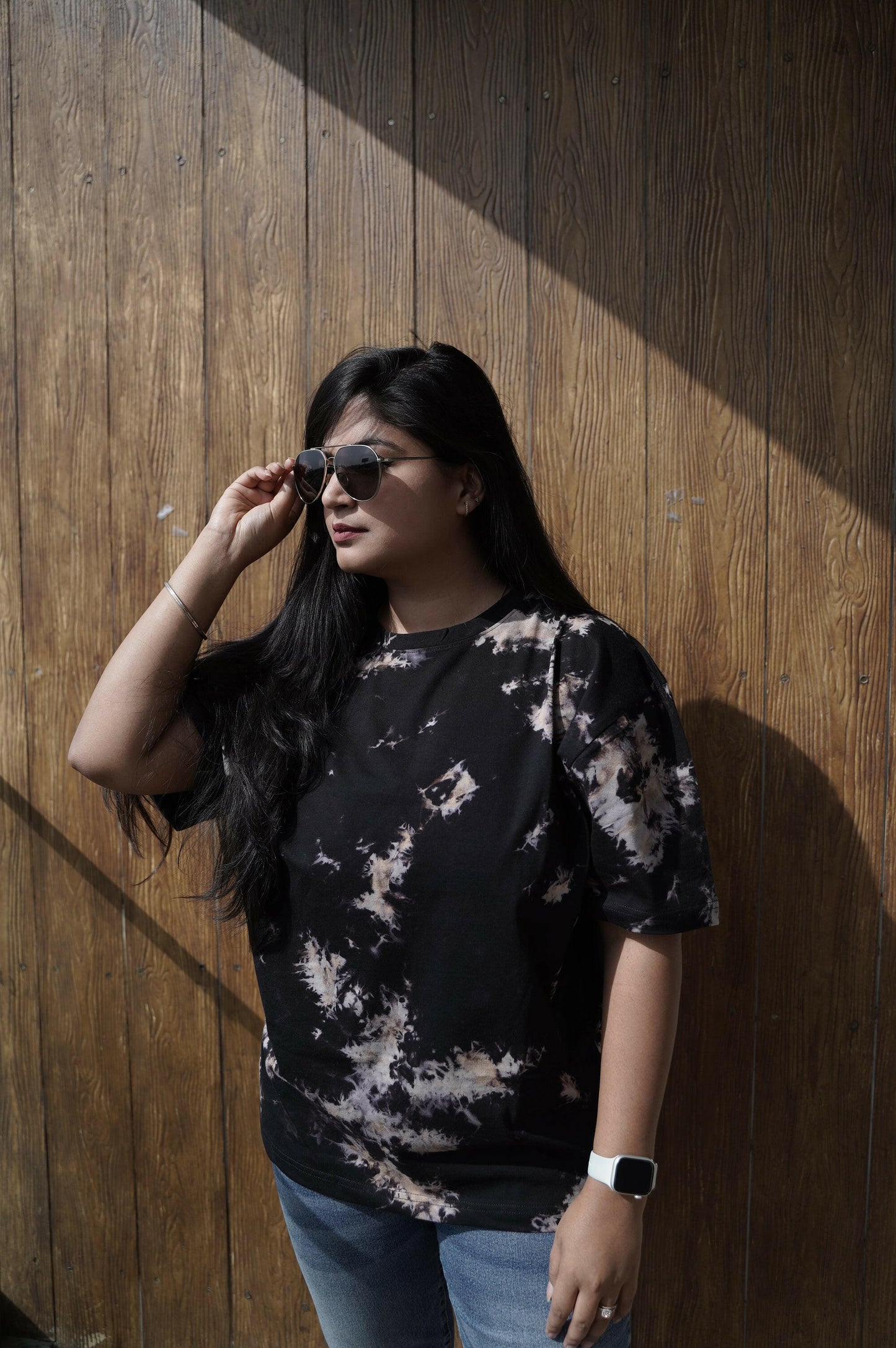 A close-up shot of a Nitorious Atelier Tie and Dye Unisex Black 100% Cotton fabric oversized T Shirt. The fabric showcases a rich black hue with intricate tie and dye patterns, crafted with high-quality cotton material.