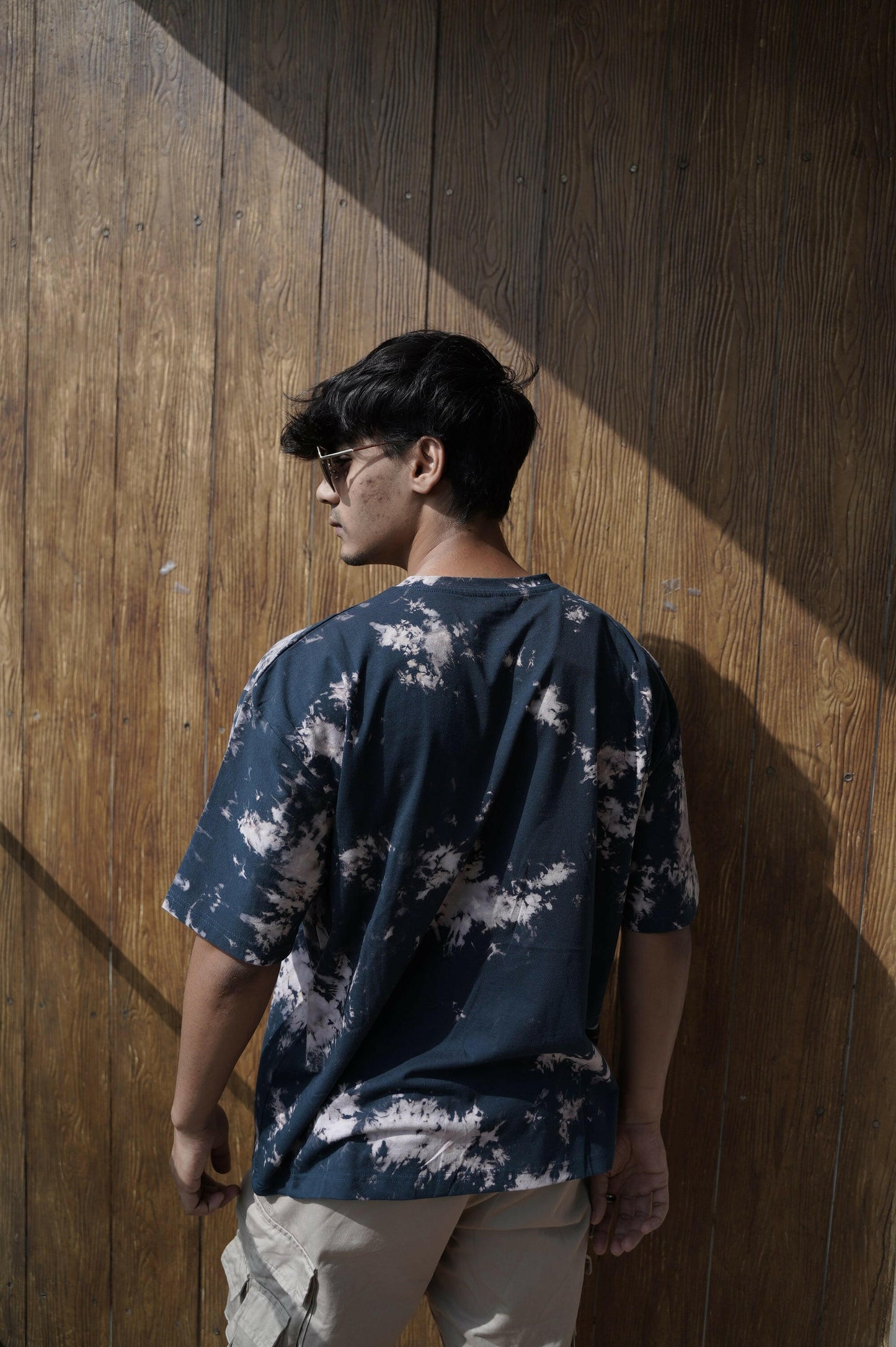 A close-up shot of a Nitorious Atelier Tie and Dye Dark Blue 100% Cotton fabric Unisex Oversized T shirt. The fabric showcases a rich black hue with intricate tie and dye patterns, crafted with high-quality cotton material.