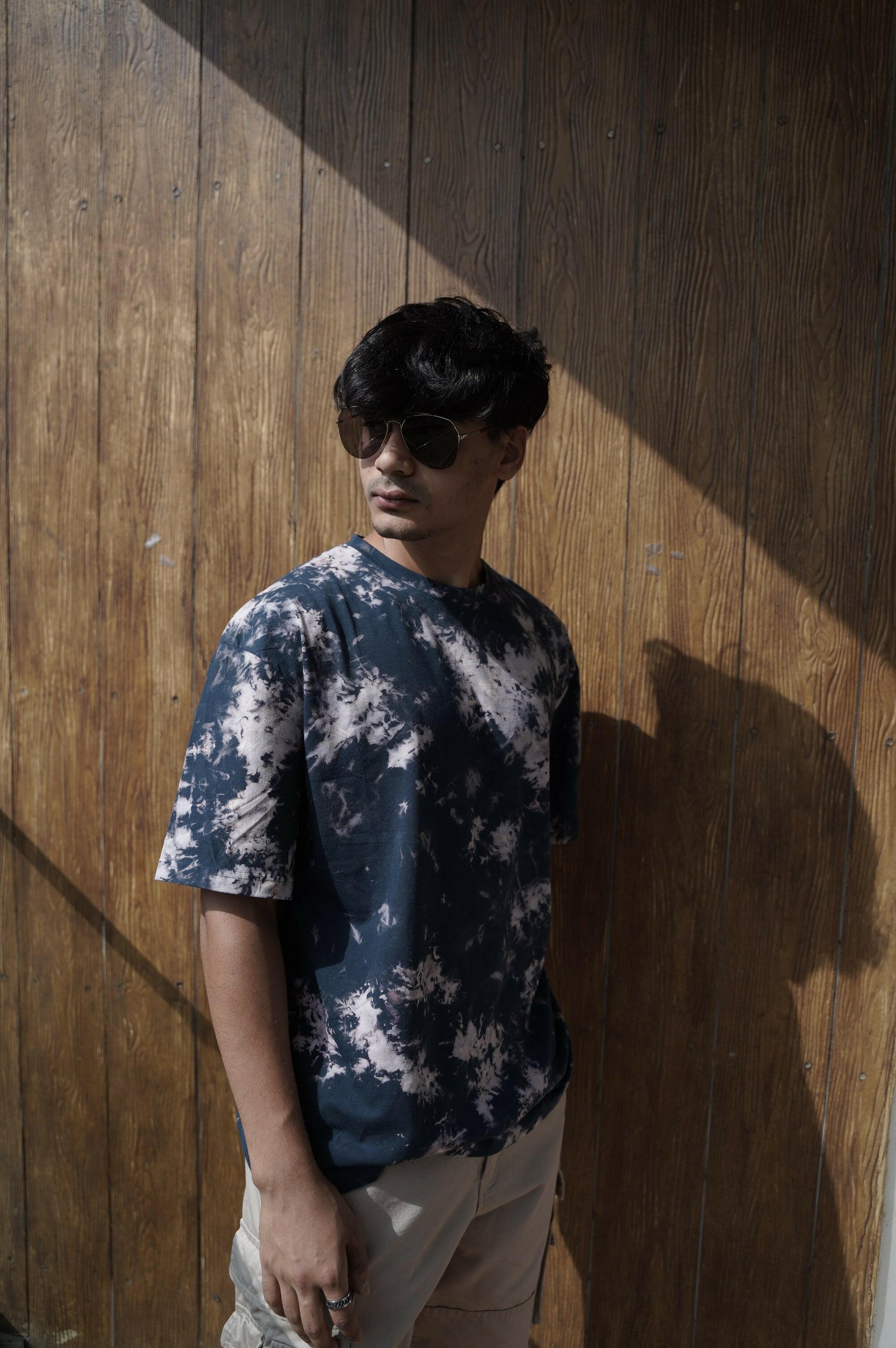 A close-up shot of a Nitorious Atelier Tie and Dye Dark Blue 100% Cotton fabric Unisex Oversized T shirt. The fabric showcases a rich black hue with intricate tie and dye patterns, crafted with high-quality cotton material.