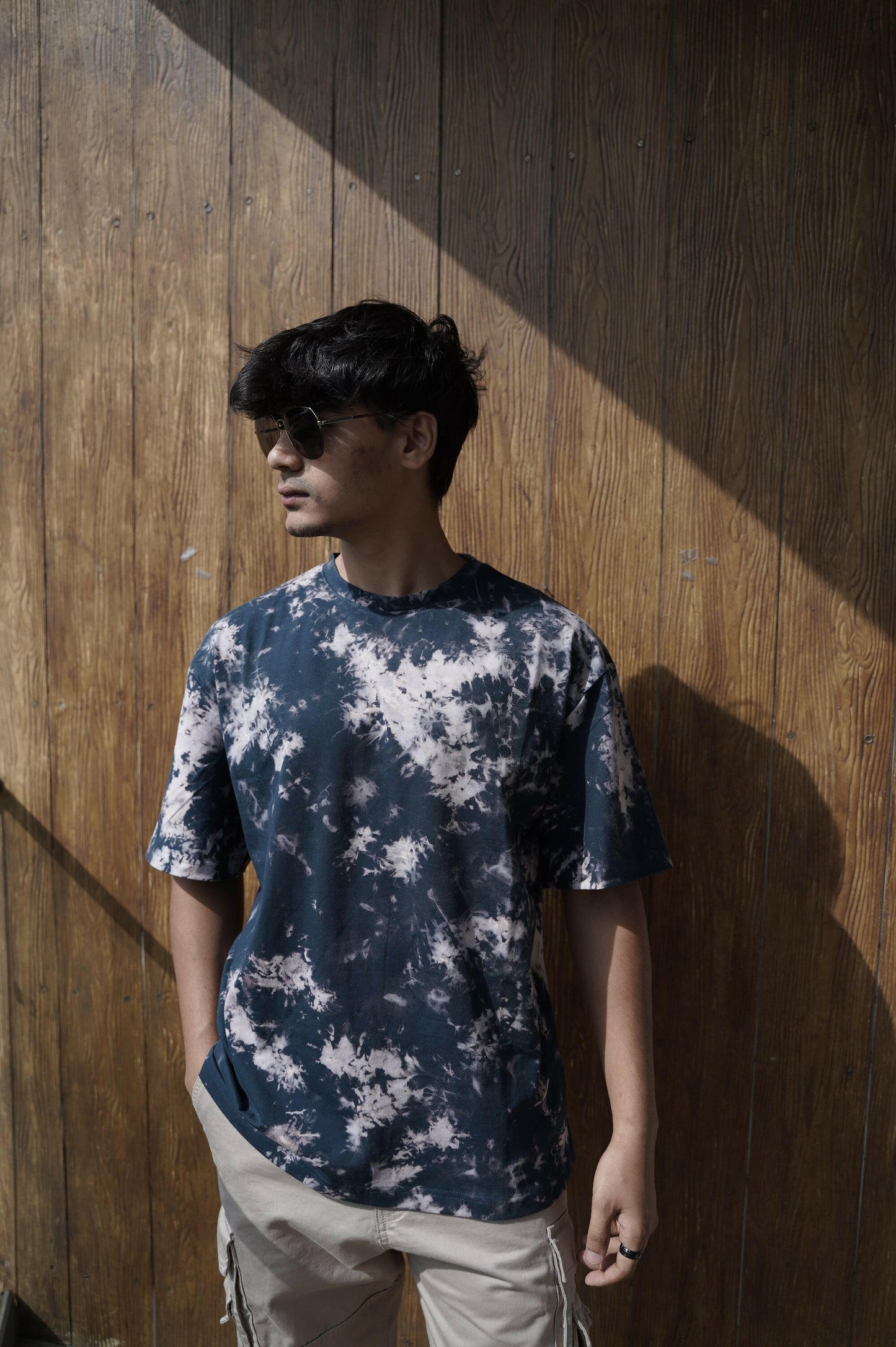 A close-up shot of a Nitorious Atelier Tie and Dye Dark Blue 100% Cotton fabric Unisex Oversized T shirt. The fabric showcases a rich black hue with intricate tie and dye patterns, crafted with high-quality cotton material.