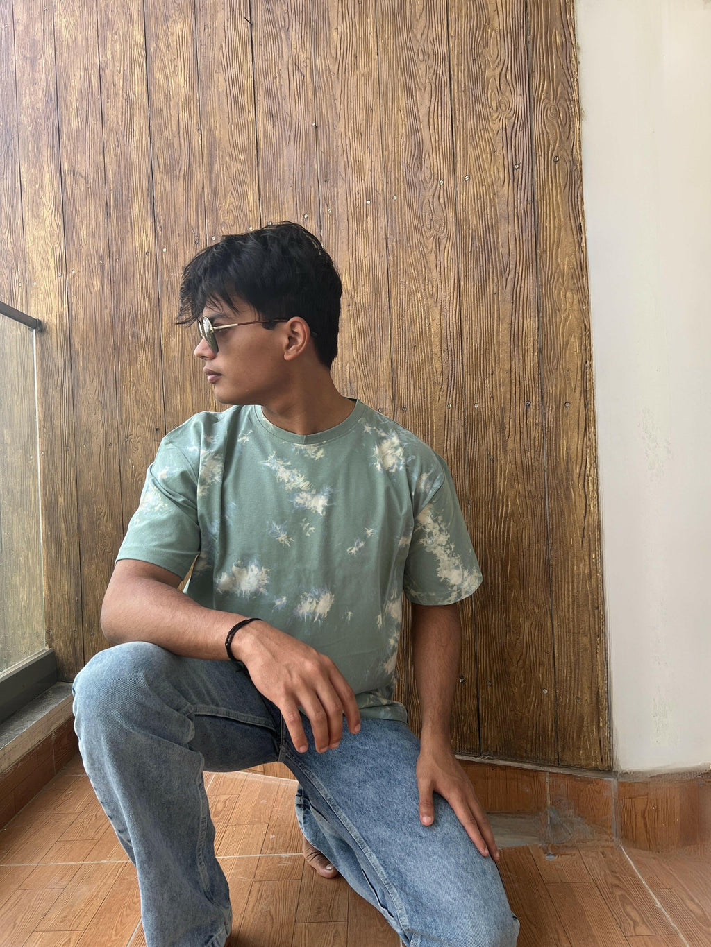 A close-up shot of a Nitorious Atelier Tie and Dye Sea Green 100% Cotton fabric Unisex Oversized T-shirt. The fabric displays a rich dark blue hue with intricate tie and dye patterns, meticulously crafted with high-quality cotton material