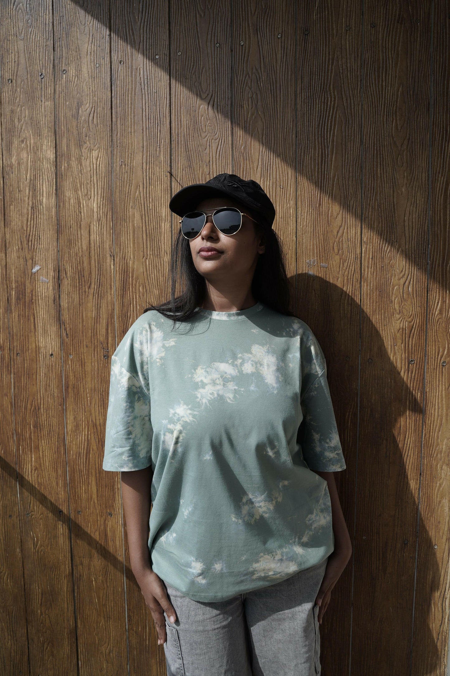 A close-up shot of a Nitorious Atelier Tie and Dye Sea Green 100% Cotton fabric Unisex Oversized T-shirt. The fabric displays a rich dark blue hue with intricate tie and dye patterns, meticulously crafted with high-quality cotton material