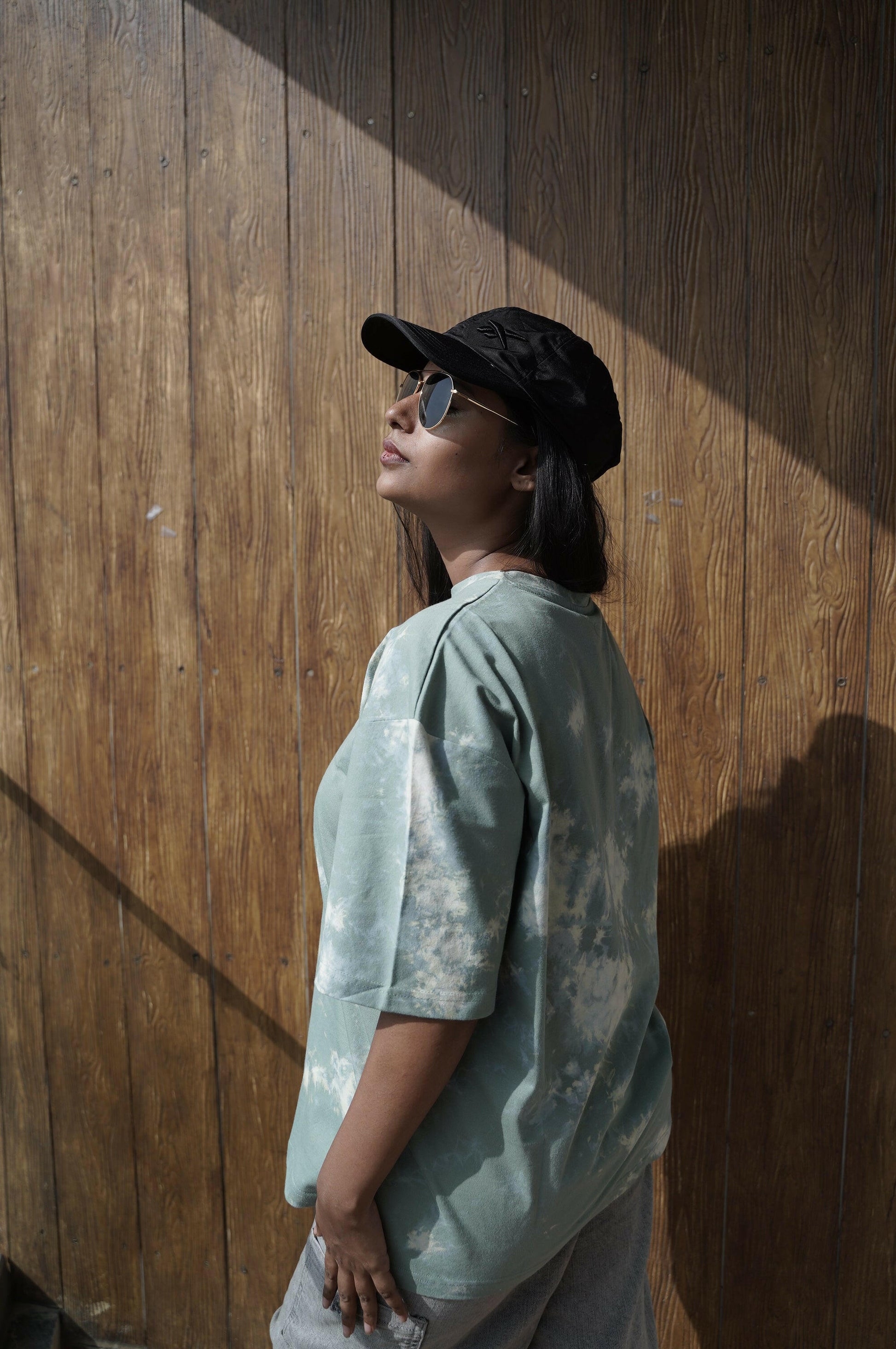 A close-up shot of a Nitorious Atelier Tie and Dye Sea Green 100% Cotton fabric Unisex Oversized T-shirt. The fabric displays a rich dark blue hue with intricate tie and dye patterns, meticulously crafted with high-quality cotton material