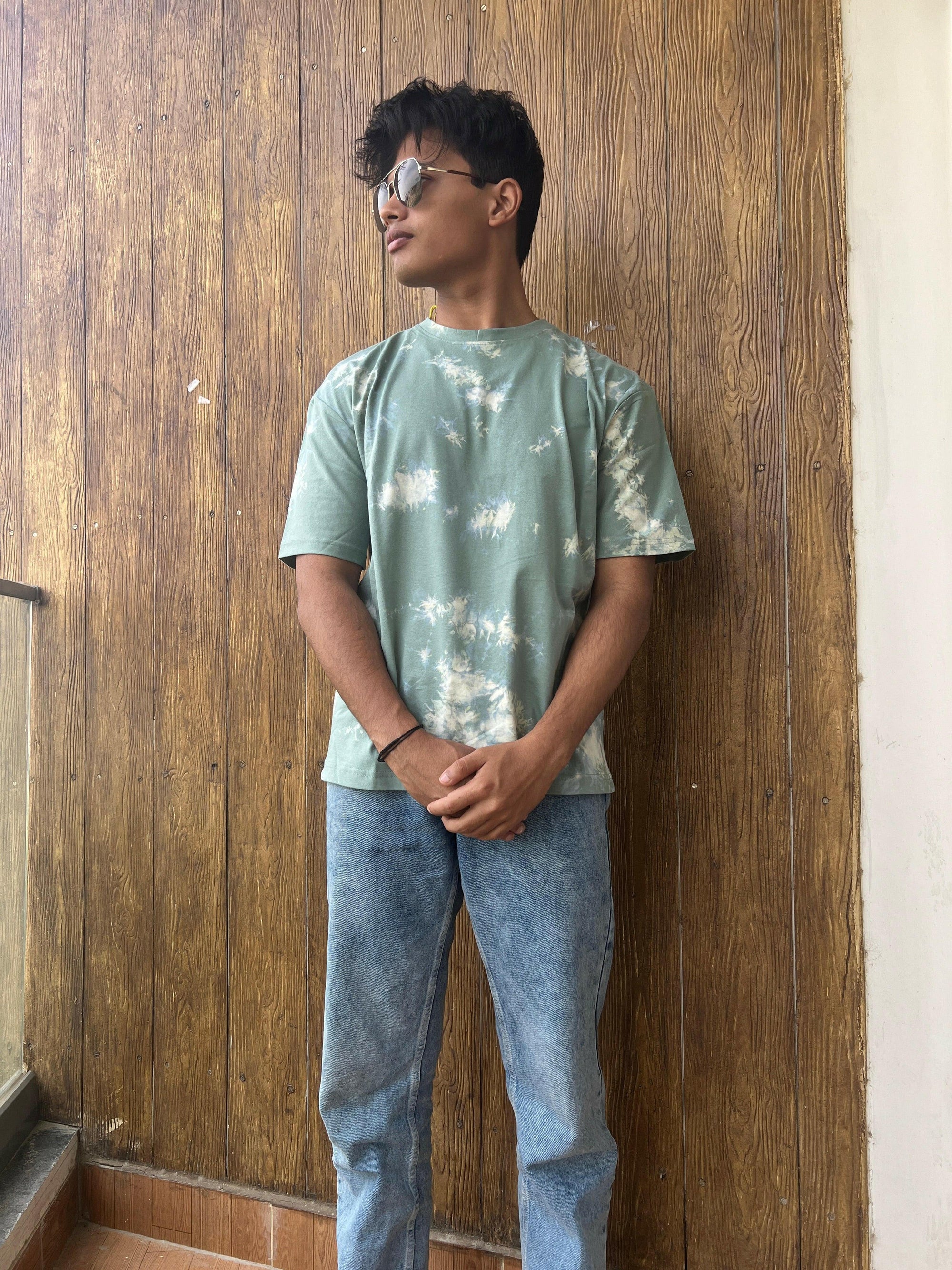 A close-up shot of a Nitorious Atelier Tie and Dye Sea Green 100% Cotton fabric Unisex Oversized T-shirt. The fabric displays a rich dark blue hue with intricate tie and dye patterns, meticulously crafted with high-quality cotton material