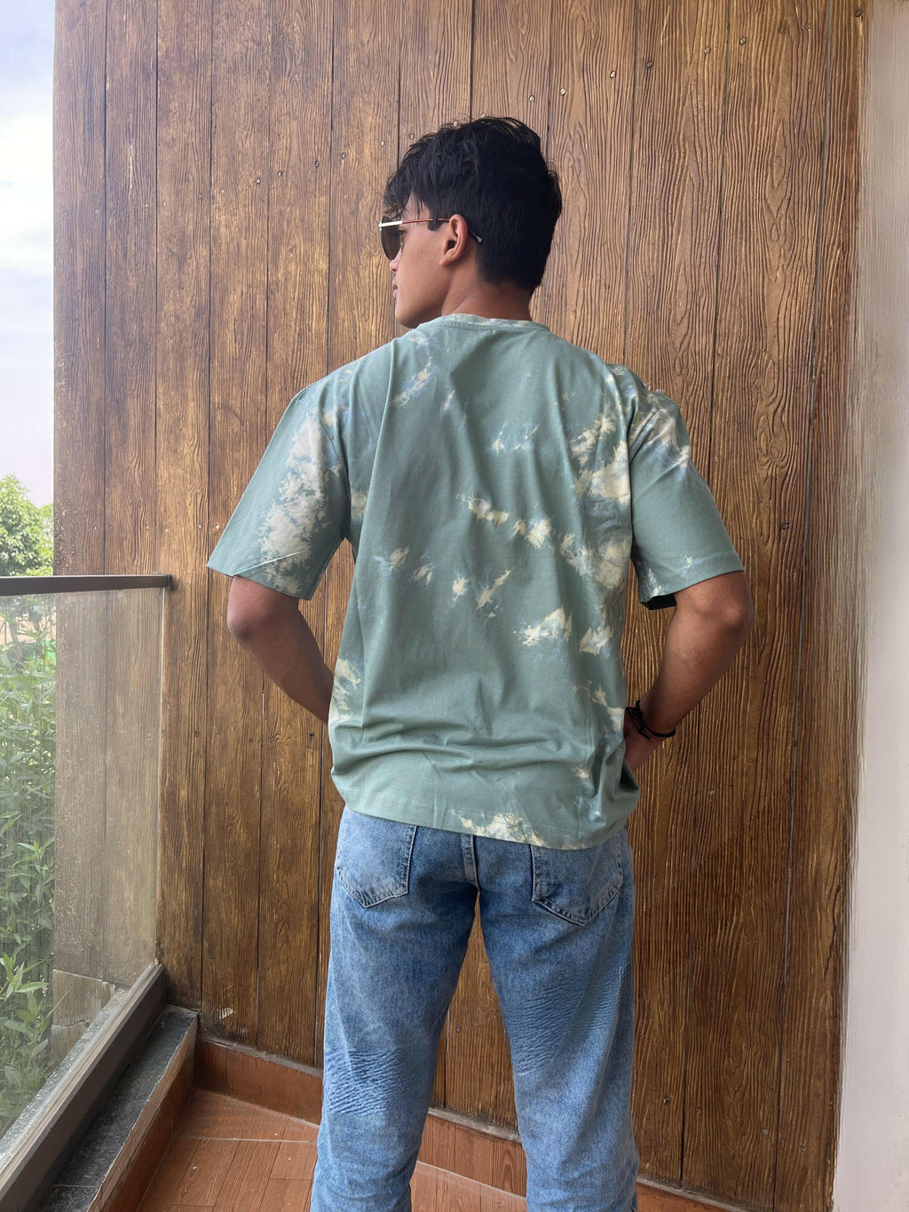 A close-up shot of a Nitorious Atelier Tie and Dye Sea Green 100% Cotton fabric Unisex Oversized T-shirt. The fabric displays a rich dark blue hue with intricate tie and dye patterns, meticulously crafted with high-quality cotton material
