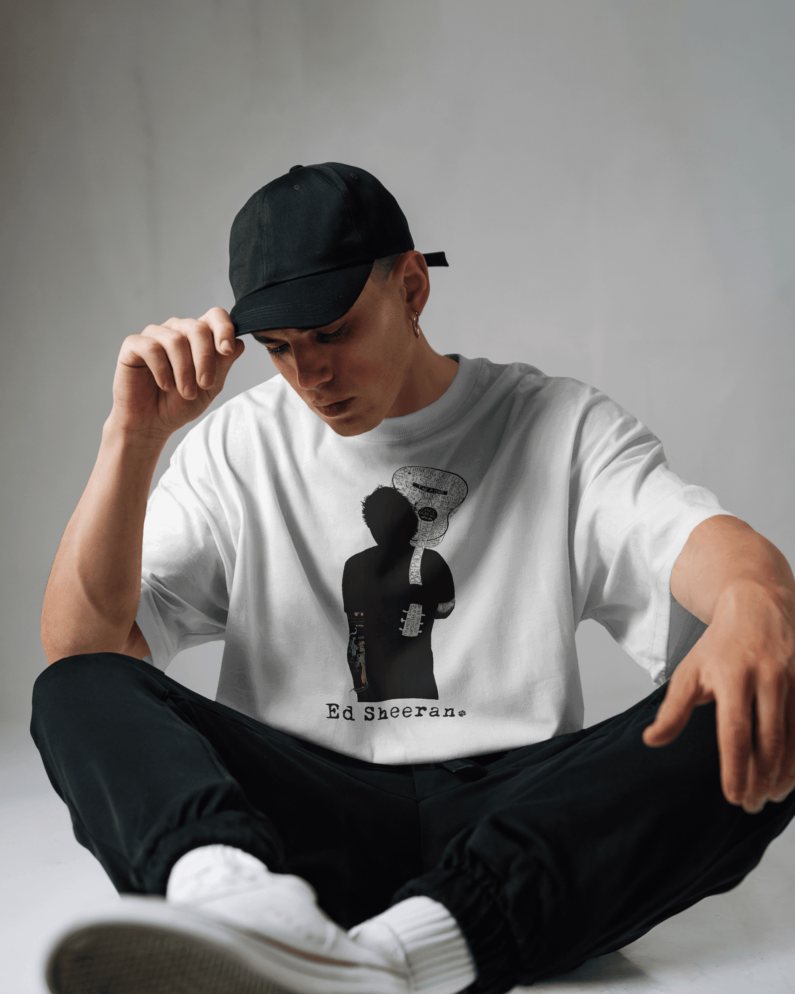 Ed Sheeran Guitar Photo White Oversized T-shirt by Nitorious Atelier. Featuring a striking photo of Ed Sheeran with his guitar, this white oversized t-shirt is crafted from premium cotton, offering ultimate comfort and a stylish fit for music fans and casual wear lovers.