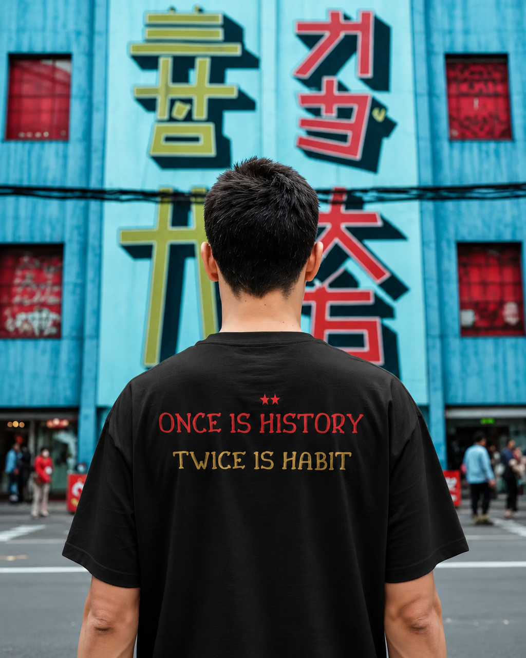 Person wearing a black t-shirt with text in front of a colorful building. RCB Champions Tshirt from Nitorious Atelier 