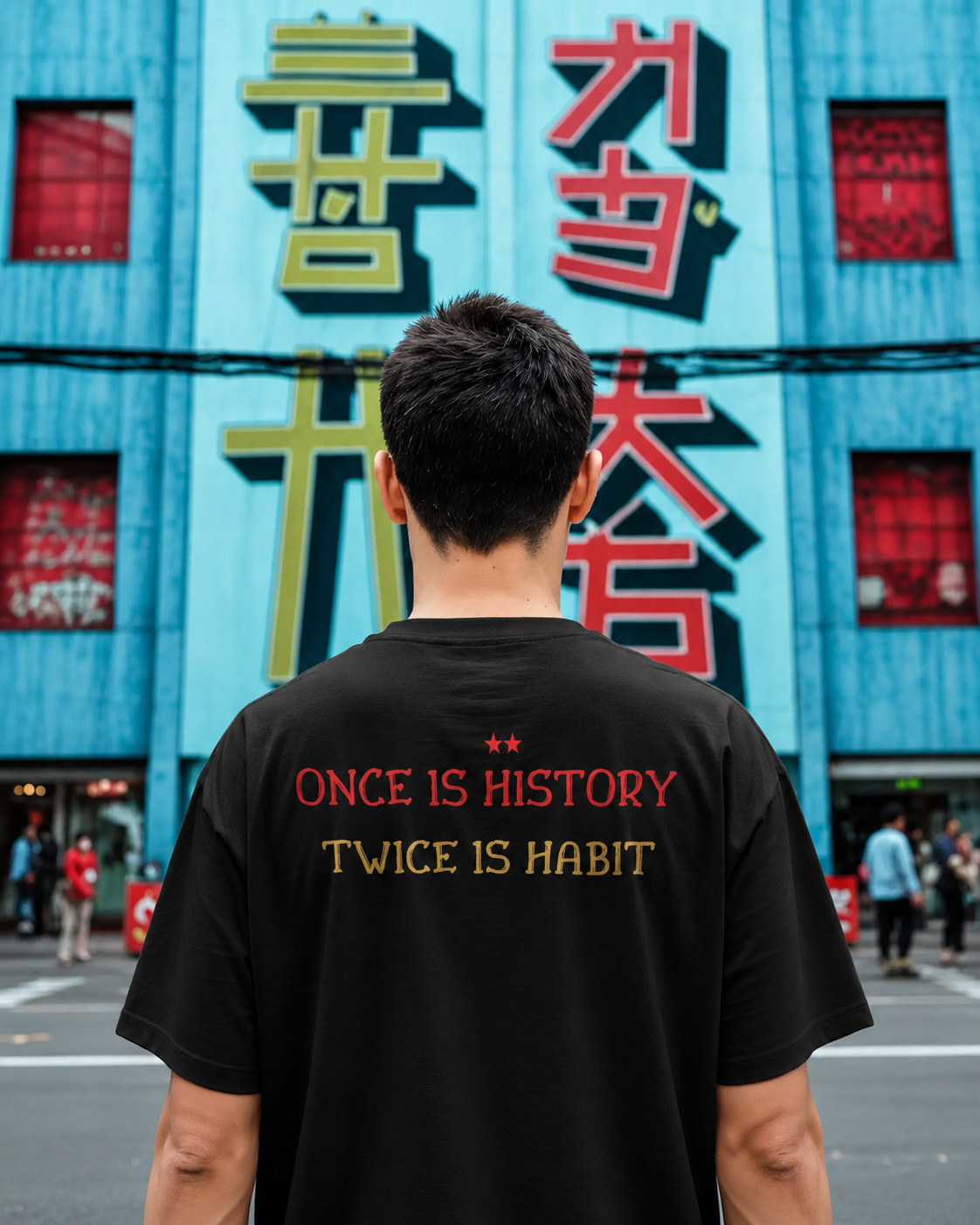 Person wearing a black t-shirt with text in front of a colorful building. RCB Champions Tshirt from Nitorious Atelier 