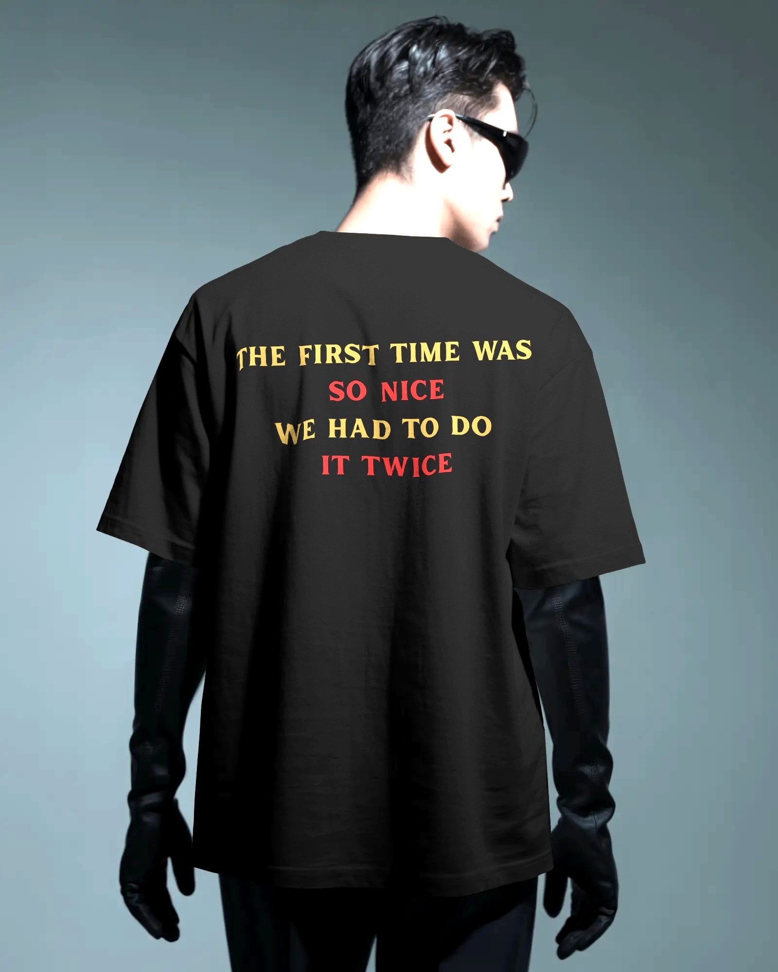 Person wearing a black t-shirt with a humorous message on the back against a gray background.  Nitorious Atelier RCB Champions 2026 Tshirt from Puma