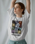 Woman wearing a white t-shirt with Shakira graphic design on a plain background