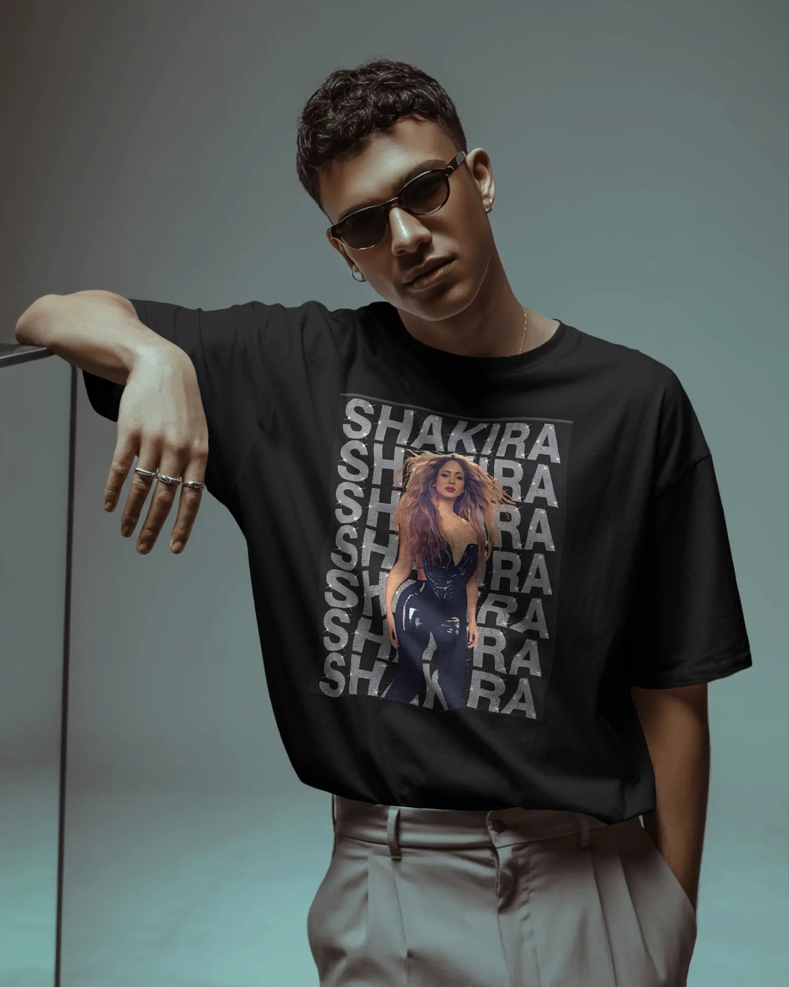 Person wearing a black t-shirt with 'Shakira' graphic design on a gray background