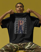 Person wearing a black t-shirt with Shakira graphic and text on a yellow background