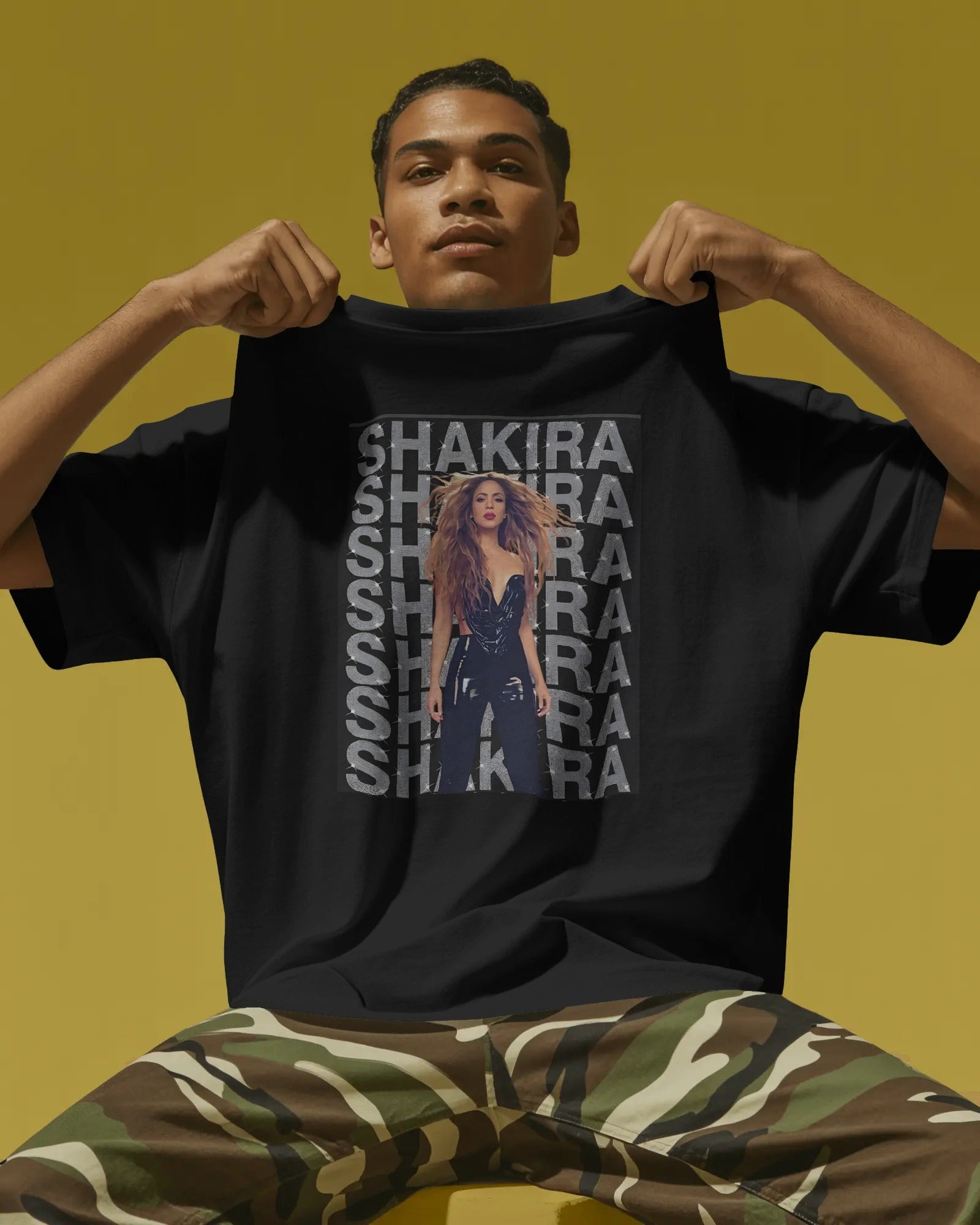Person wearing a black t-shirt with Shakira graphic and text on a yellow background