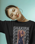 Person wearing a black shirt with 'Shakira' printed multiple times on a light blue background