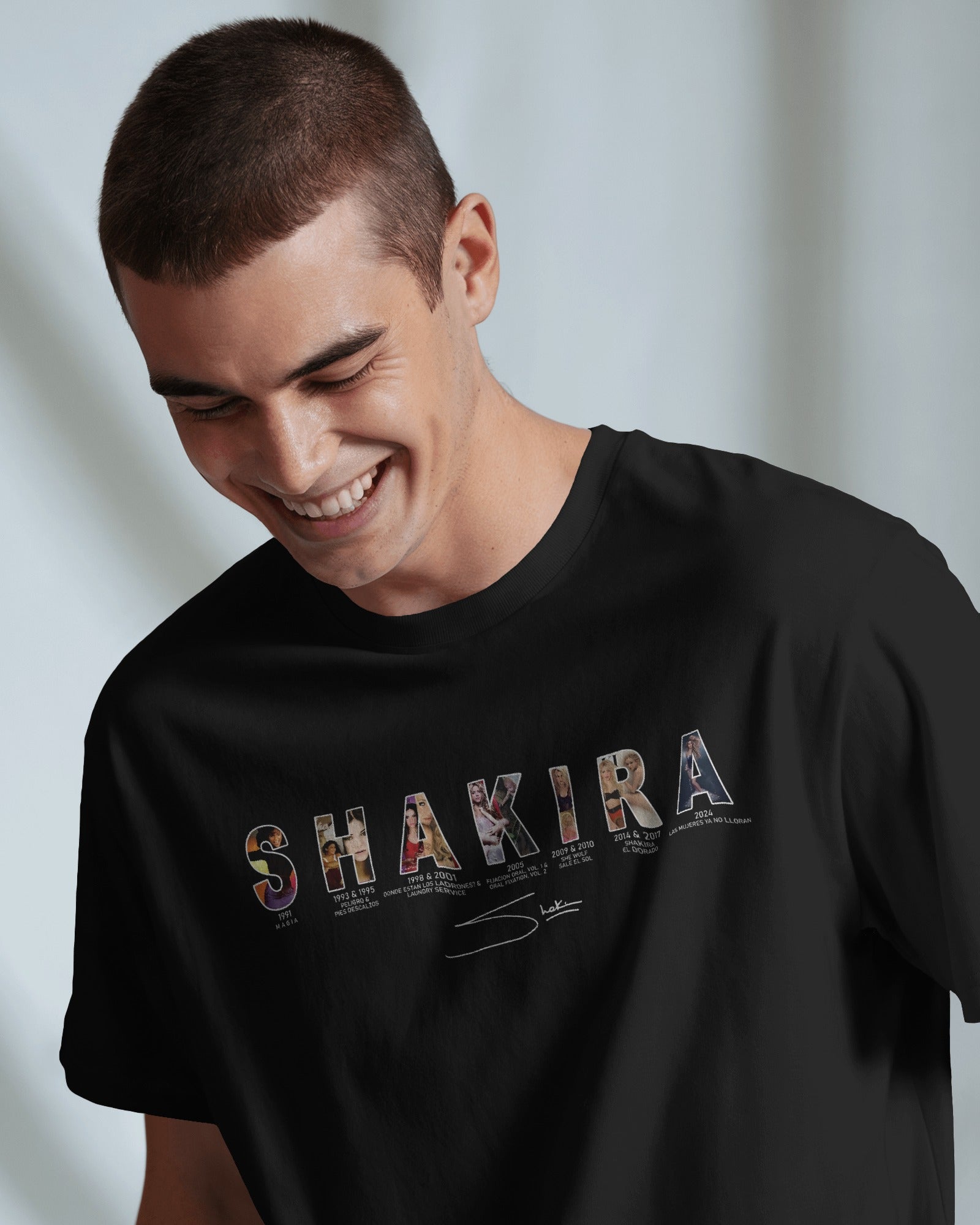 Man wearing a black t-shirt with 'SHAKIRA' design on a light background