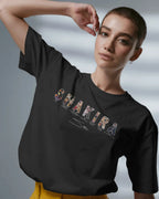 Person wearing a black t-shirt with 'Shakira' design on a gray background