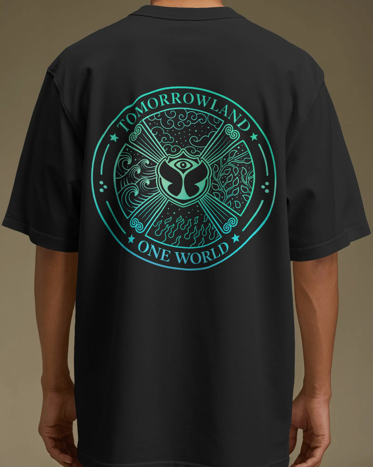 A person wearing a black short-sleeve T-shirt shown from the back, featuring a large circular teal graphic with the words 'TOMORROWLAND' and 'ONE WORLD' around an eye motif and decorative symbols.
